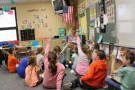 Class of elementary students raising hands to answer a question